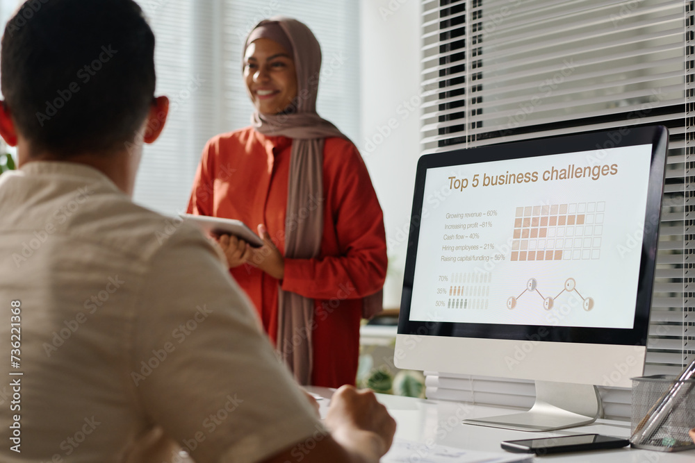 Poster screen of desktop computer with top five business challenges and graphic data against young muslim w