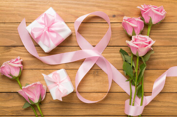 Composition with pink roses, gift box and eight made of ribbon on wooden background, top view. Women's day concept