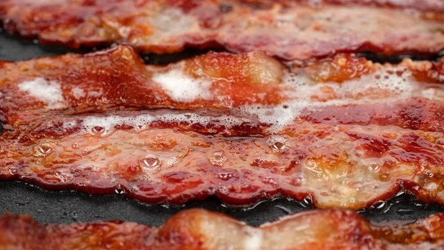 Bacon. Sliced bacon fried in pan, slider shot