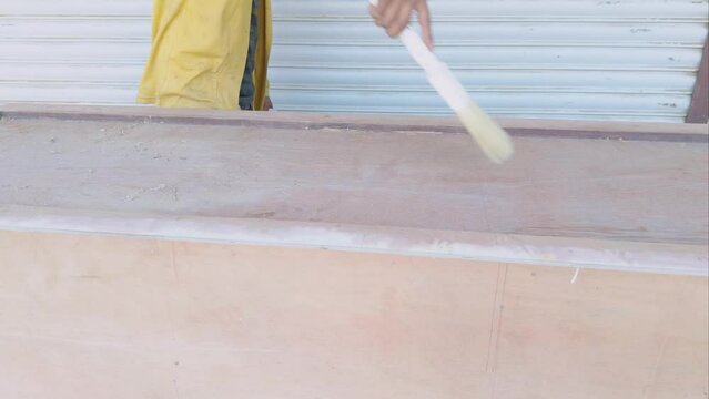 painter applying vanish or cleaning with brush primer on a wood cabinet furniture on carpenter shop with a roller brush