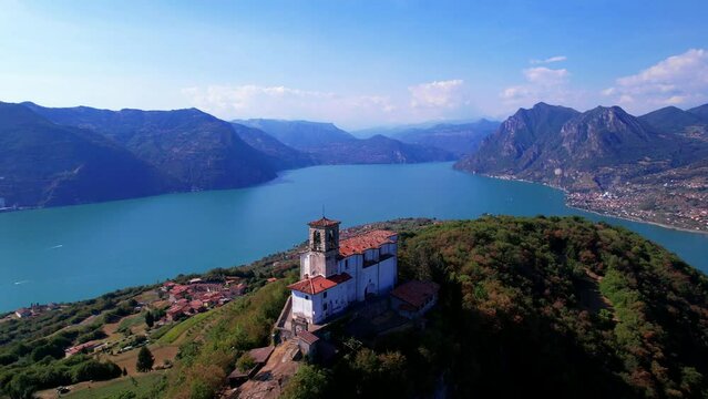 Scenic romantic lakes of Italy - Lago Iseo surrounded by beautiful mountains. Aerial view of small church in top of Monte isola island. Popular tourist attraction
