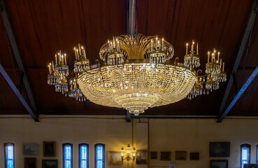 One of three large ornate chandeliers in this banquet hall in Upstate NY.  Old antique light hangs from the ceiling in this historic building in NY.