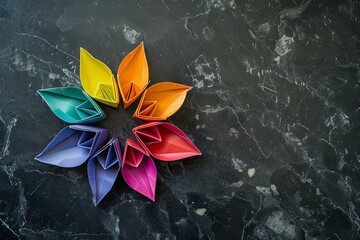 A vibrant flower origami on black marble with rainbow hues - obrazy, fototapety, plakaty