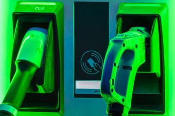 Close up of a electric car charger in green neon light at night