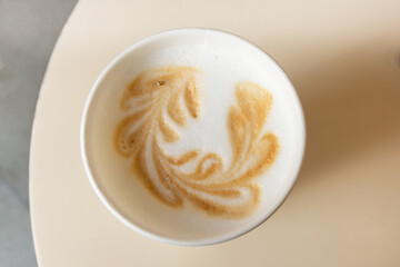 There is a cup of latte on the table in the cafe. Top view of latte art