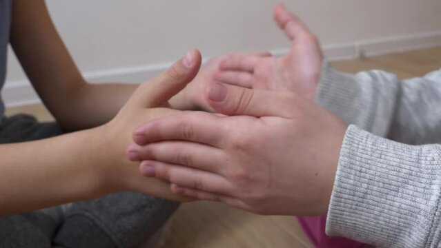 Two kids playing a hand palms clapping game in the room, a close-up view.