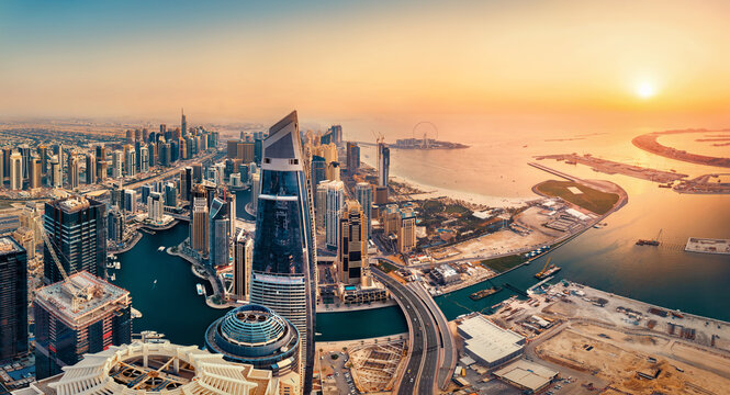 View of the Dubai skyline at sunset from above, warm earth colors in beautiful contrast to the dark teal of the water