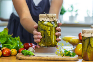 Woman canning vegetables in jars in the kitchen. Selective focus.