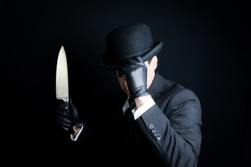 Portrait of Man in Dark Suit and Leather Gloves Holding Sharp Knife. Well Dressed Gentleman Killer....