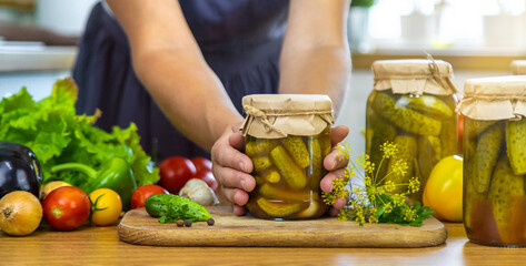 Woman canning vegetables in jars in the kitchen. Selective focus.