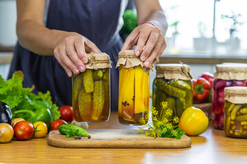 Woman canning vegetables in jars in the kitchen. Selective focus.