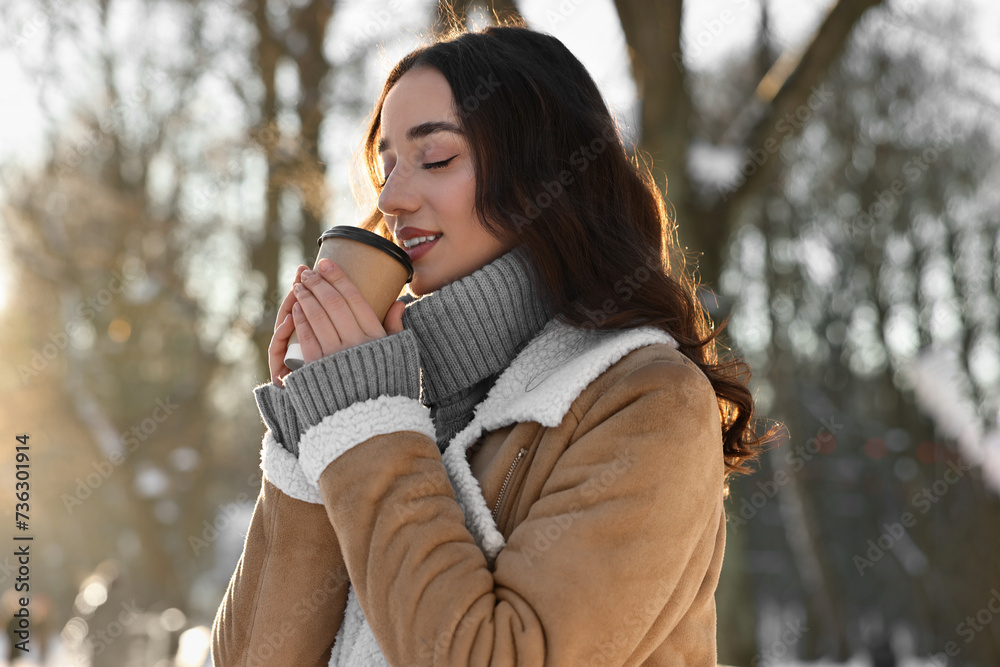 Wall mural Portrait of beautiful woman drinking coffee in snowy park