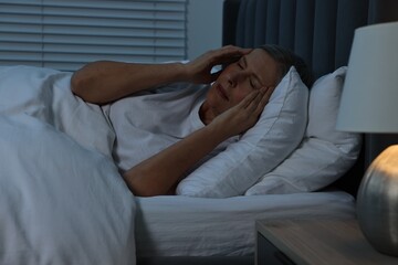 Woman suffering from headache in bed at night