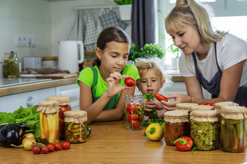 Family canning vegetables in jars in the kitchen. Selective focus.