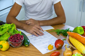 A nutritionist writes a nutrition plan. Selective focus.