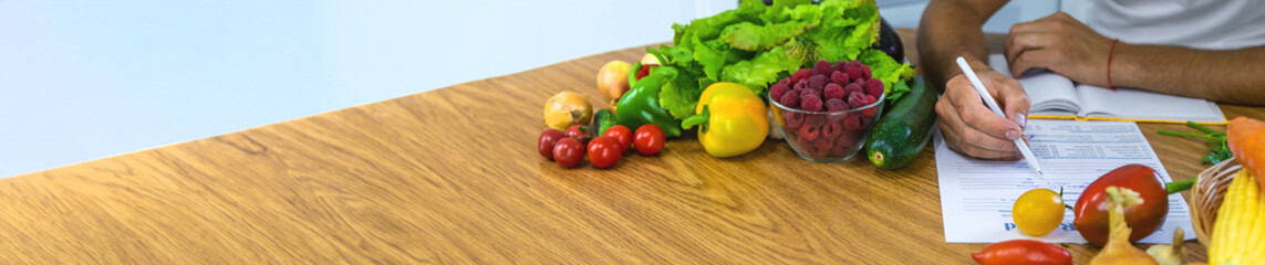 A nutritionist writes a nutrition plan. Selective focus.