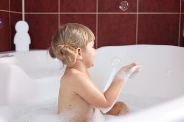 Little girl having fun in bathtub at home