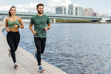 Active couple running by the river in city, healthy lifestyle and teamwork.