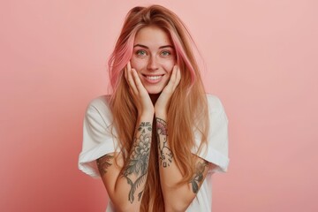 Smiling Caucasian woman with long hair pink tips and tattoos on arms wearing a white T shirt hides face with hair looks happily at camera