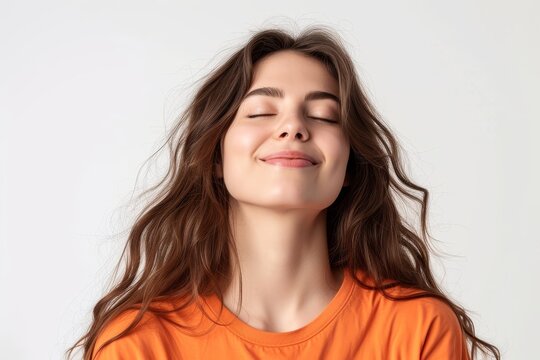 Portrait of a joyful woman with closed eyes smiling freely wearing a white t shirt on a white background
