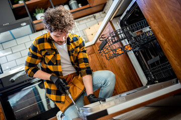 Latino man fixing dishwasher.