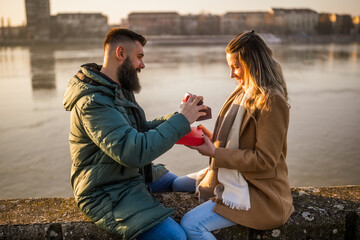 Fototapeta premium Man giving presents to his woman while they enjoy spending time together outdoor.