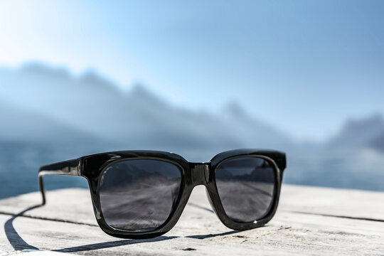 Sonnenbrille auf einem Holztisch mit Schneebergen im Hintergrund