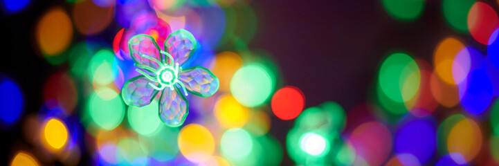 Multicolored garland flower against background of multicolored lights on Christmas night, beautiful...