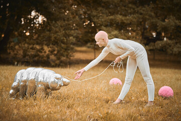 Portrait of young hairless girl with alopecia in white cloth playing with tardigrade toy in fall...
