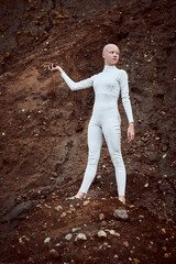 Full length portrait of young hairless girl with alopecia in white futuristic suit holding handful...