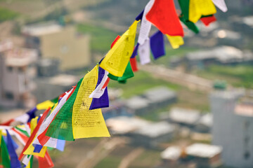 Colorful Tibetan prayer flags on blurred Kathmandu cityscape background symbolizing cultural value...