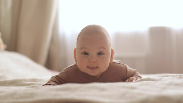 baby lying on his stomach in bed at home smiling slow motion close-up
