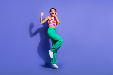 Fototapeta na wymiar Full body length photo of young lady dj loves music hipster jumping in wireless pink earphones isolated on violet color background