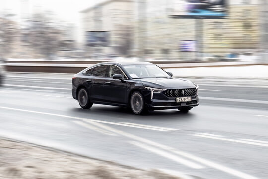 FAW Bestune B70 rides on a street. Black chinese 5-door sedan motor car rushes on the road with blurred background