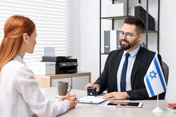 Smiling embassy worker consulting woman about immigration to Israel in office