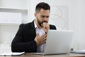 Sick man coughing at workplace in office