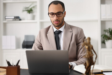 Serious lawyer working with laptop at table in office