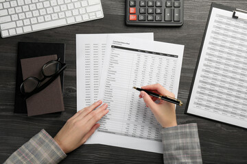 Woman working with accounting documents at wooden table, top view
