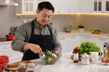 Man cooking fresh salad at countertop in kitchen