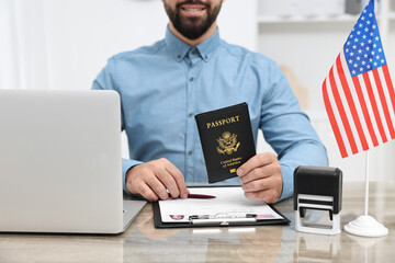 Immigration to United States of America. Smiling embassy worker with passport and documents at wooden table in office, closeup - obrazy, fototapety, plakaty