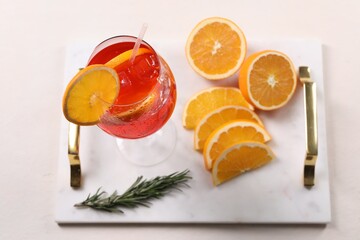 Glass of tasty Aperol spritz cocktail with orange slices and rosemary on white table, above view