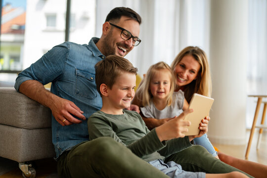 Happy young family having fun time at home. Parents with children using tablet