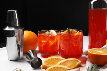 Aperol spritz cocktail, rosemary and orange slices on white table