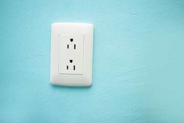 Imagen de un contacto para electricidad de una casa sobre una pared azul