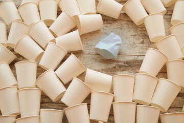 White paper cups scattered on the table and one crumpled among them
