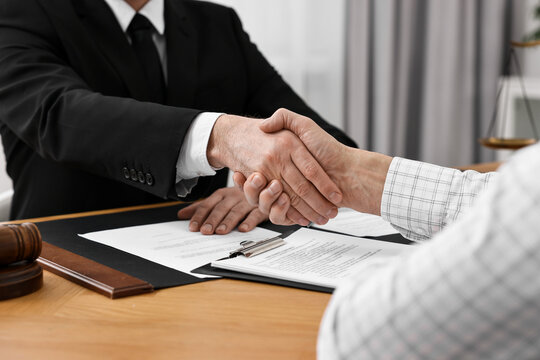 Lawyer shaking hands with client in office, closeup