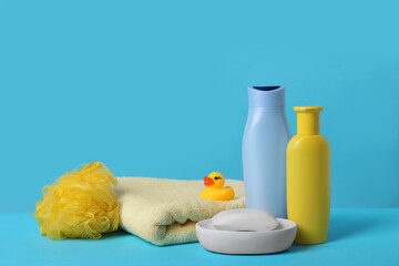 Baby cosmetic products, bath duck, sponge and towel on light blue background. Space for text