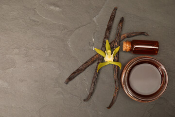 Aromatic vanilla extract, pods and flower on black table, flat lay. Space for text