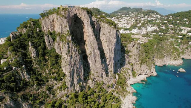 Capri Island with rocky natural arch formations. High cliffs and deep blue sea in Italy. Summer popular tourist destination.