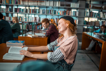 Smiling young woman reading a book in college library